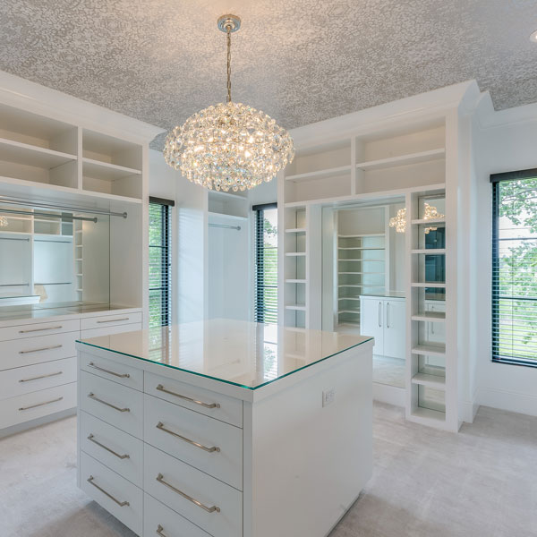 walk in closet with white cabinets and chandelier