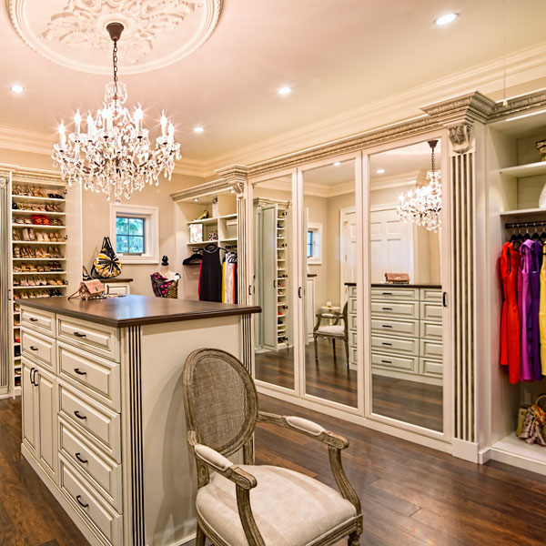 walk in closet with white cabinets, wood accents and chandelier